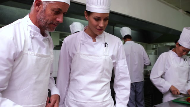 Head chef showing another how to make pizza