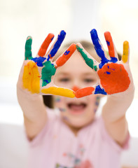 Portrait of a cute girl playing with paints