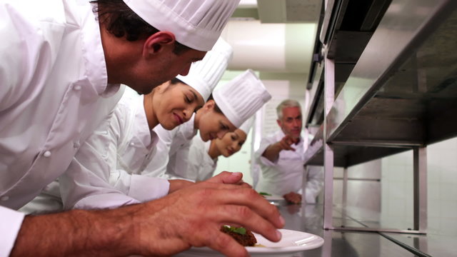 Head chef supervising his team garnishing plates