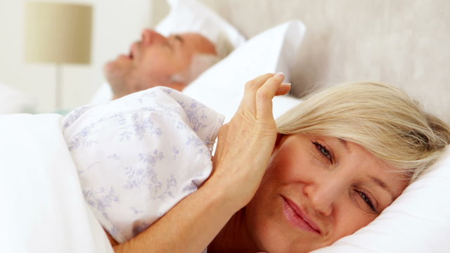 Woman covering her ears as partner is snoring loudly
