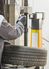 Mechanic changing car tire with bead breaker tool.