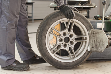 Mechanic changing car tire with bead breaker tool.