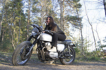 Plakat Sexy brunette woman driving a motorcycle in the forest