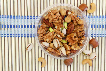 Selection of mixed nuts in wooden bowl on bamboo mat