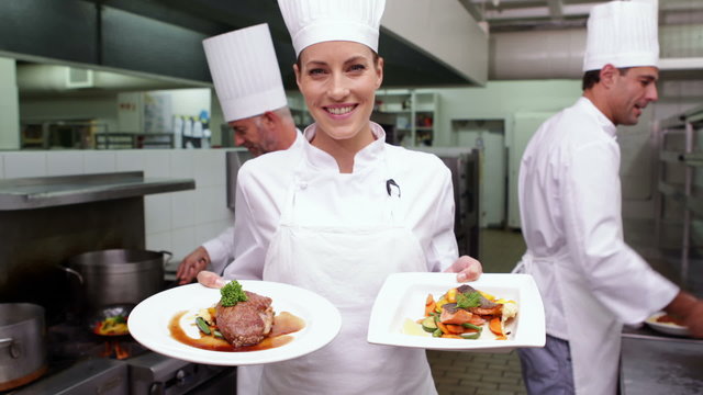 Smiling chef showing two dishes to camera