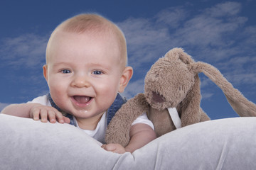 happy baby with cuddle against blue sky