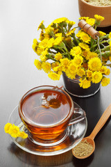 mortar, pestle and bucket with coltsfoot flowers