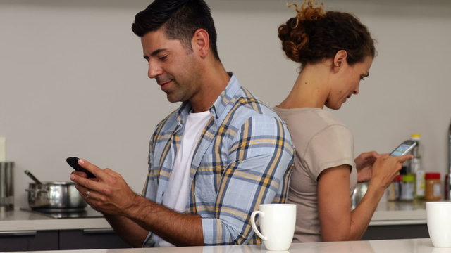 Couple sitting back to back texting each other