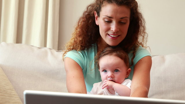 Mother using laptop with baby son on her lap