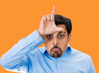 Bully guy giving Loser hand gesture on orange background 