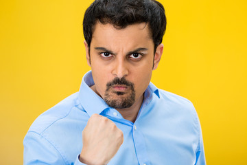 Portrait angry man with fist up, isolated yellow background 