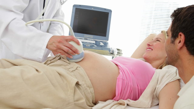 Blonde pregnant woman having a sonogram scan with her partner
