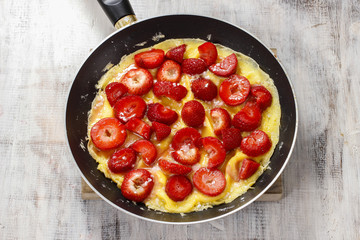 Strawberry omelette on frying pan