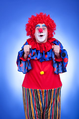 Happy clown in red costume on blue background