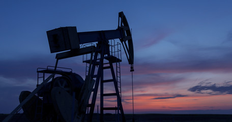 Operating oil and gas well profiled on sunset sky