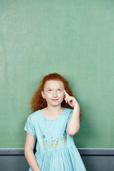 Mädchen vor Tafel denkt nach