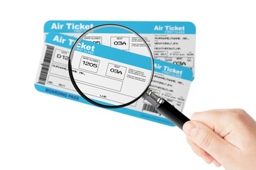 Airline boarding pass tickets with magnifier glass in hand