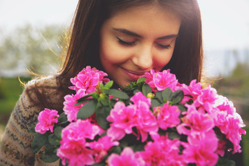 Fototapeta premium Young cute woman smelling pink flowers