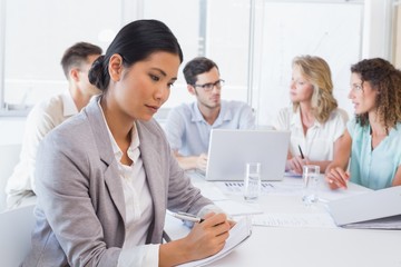 Fototapeta premium Casual businesswoman taking notes during meeting
