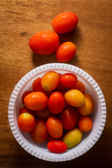 Tomatoes with white bowl on wood table.