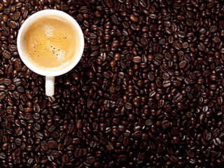 Top view of a cup of dark roasted coffee with coffeebeans