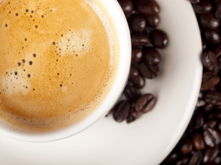 Top view of a cup of dark roasted coffee with coffeebeans