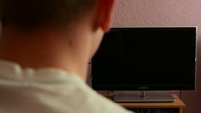 Man watches TV - green screen - man turns on television