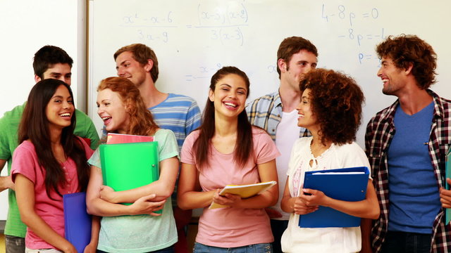 Students standing in classroom giving thumbs to camera