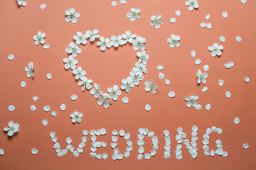 Word WEDDING and a heart as a symbol of love made of flowers.