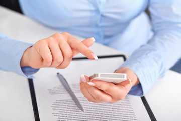 Young woman working with a mobile phone above the contract