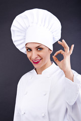 Attractive cook woman showing ok over dark background