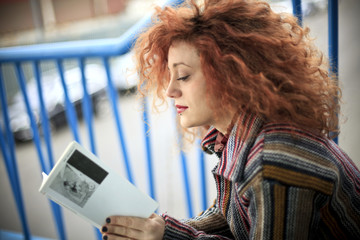 Beautiful girl reading a book on a balcony