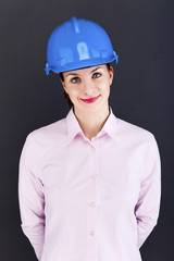 Woman architect, contractor in blue helmet over dark background