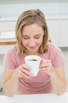 Eelaxed young woman having coffee in kitchen