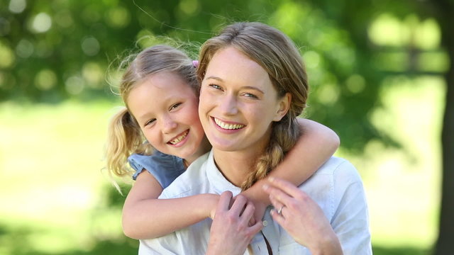 Happy little girl hugging mother in the park