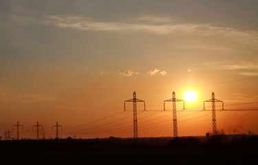 High electricity power line towers at dramatic sunset background