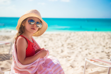 Beautiful little girl sitting on chair at beach during summer