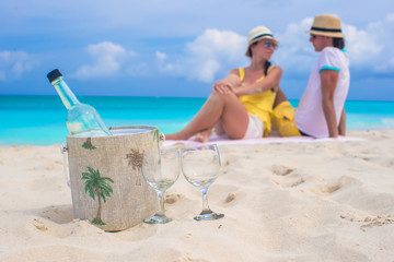 Fototapeta premium Bottle of wine and two glasses background happy couple at beach