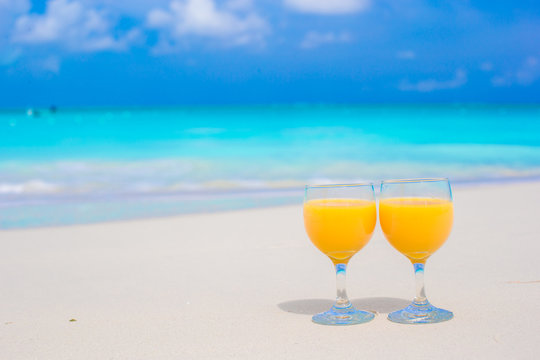 Two glasses of orange juice on tropical white beach