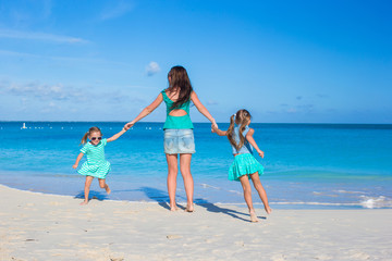 Happy mother and her adorable girls having fun at tropical beach