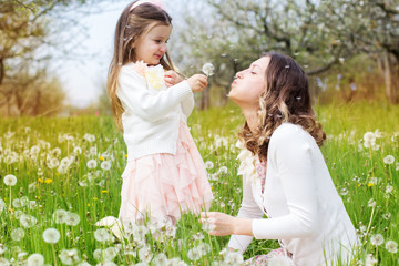 Obraz premium Mother and daughter in field with dandelions