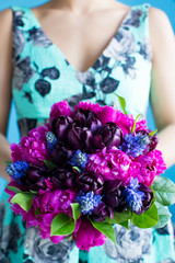 bridesmaid holds a wedding bouquet of tulips and pions in purple