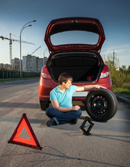 man sitting on road and leaning against broken car
