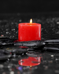 pebbles and red candle on wet background