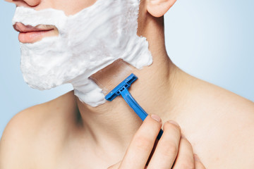 Unrecognizable man is shaving with razor
