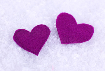 Little felt hearts on snowy background