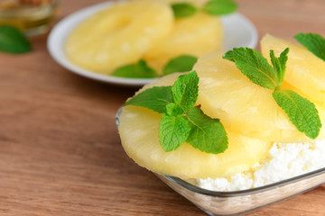 Bowl of tasty cottage cheese with pineapple on wooden table
