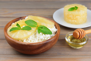 Bowl of tasty cottage cheese with pineapple on wooden table