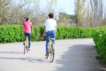 Fototapeta premium Young couple riding on bicycles in park