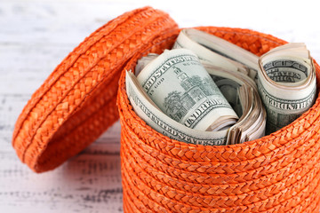 Packs of dollars stored in basket on wooden table